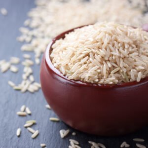 Natural rice in a red ceramic bowl on stone background. closeup Kai Kuthal Ponni